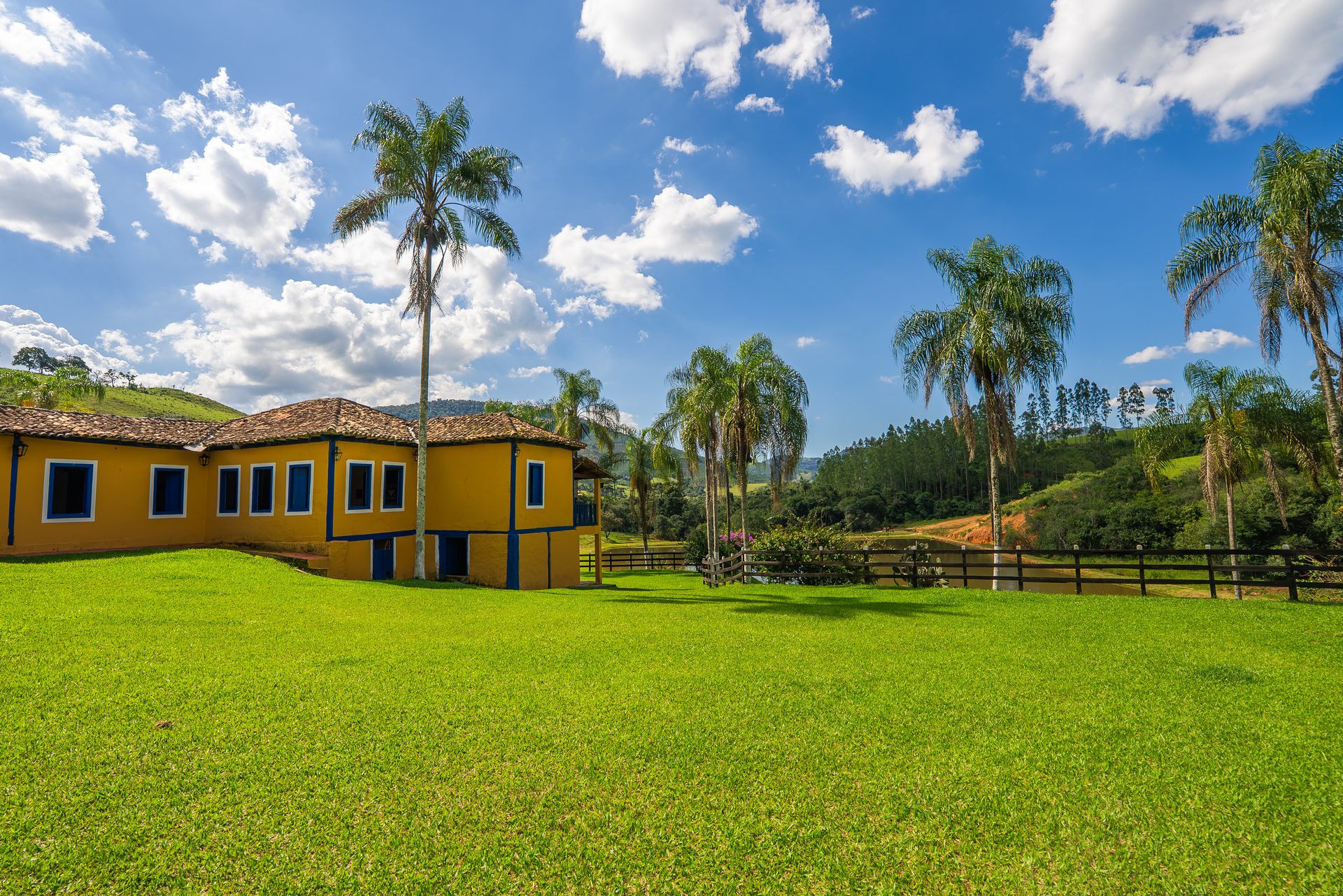 Casarão histórico bicentenário em taipa de pilão, fachada amarela com palmeiras imperiais e jardim verde